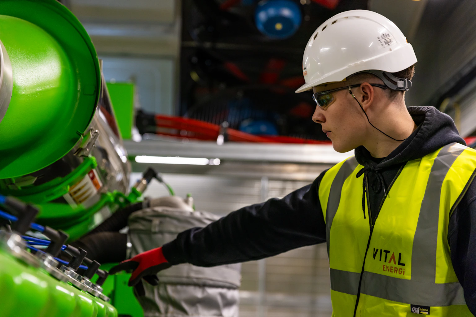 Engineer wearing a hard hat, eye protection, gloves and high-visibility clothing while working on equipment